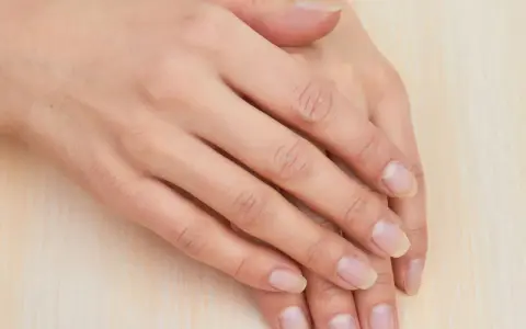 Mani curate, con unghie naturali e sane che sembrano respirare. La pelle è liscia e luminosa, poggiata su una superficie chiara.