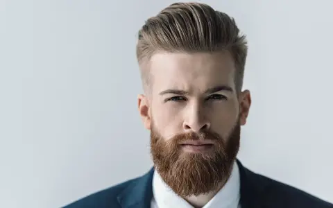 Mężczyzna z gęstą, rudą brodą, prezentujący jeden z popularnych rodzajów brody. Elegancki styl i zadbanie.