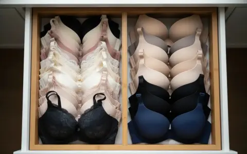Un cassetto ordinato con reggiseni coppe preformate in varie tonalità neutre e scure. Il loro significato è offrire supporto e forma.