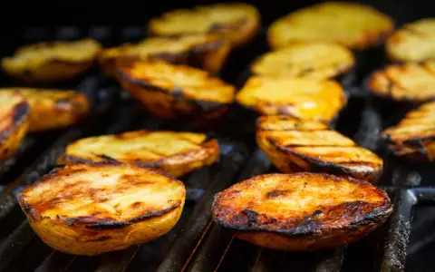 Patate alla griglia dorate e succulente, con segni di cottura perfetti, pronte per essere gustate.
