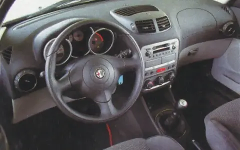 Wnętrze Alfa Romeo 147 1.9 JTD: kierownica, deska rozdzielcza z radiem i nawiewami, dźwignia zmiany biegów.