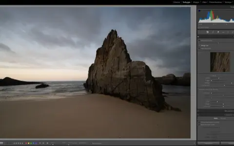 Scogliera imponente su una spiaggia al tramonto, con onde mosse. L'aggiornamento Lightroom sta migliorando i dettagli dell'immagine.