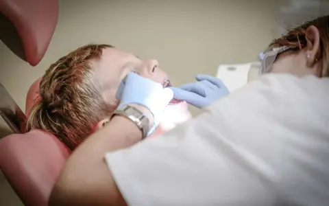 Chłopiec u dentysty, który bada jego zęby. Może to być związane z bólem podniebienia przy zębach górnych.