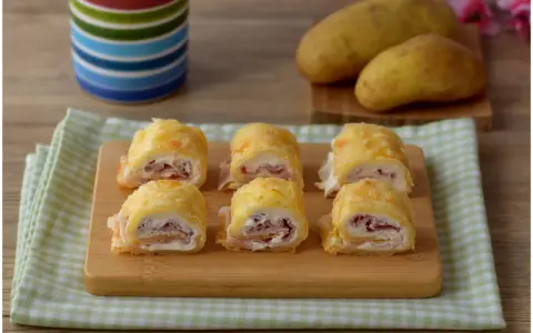 Sei rotoli di patate ripieni di prosciutto e formaggio cremoso, pronti per essere gustati.