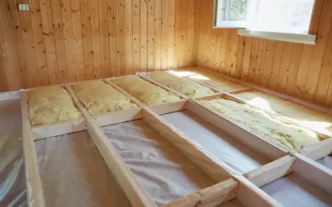 Travaux d'isolation du sol d'une maison ancienne : pose d'isolant minéral dans une structure en bois.