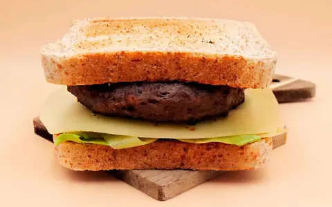 Burger z wołowiny, serem, sałatą i tostami na desce.