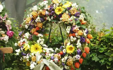 Bogaty wieniec pogrzebowy z róż, gerber, chryzantem i miechunki. Piękne kwiaty na wieniec pogrzebowy tworzą symboliczny bukiet.