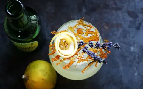 Erfrischender Drink mit Zitronenzeste, Karamell und Lavendel. Die bergamotte verwendung in Cocktails ist ein Genuss.