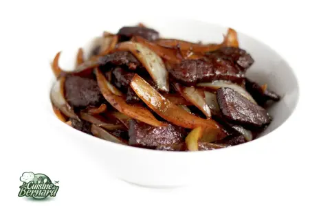 Un délicieux sauté de bœuf aux oignons caramélisés, servi dans un bol blanc. Un plat savoureux et réconfortant.