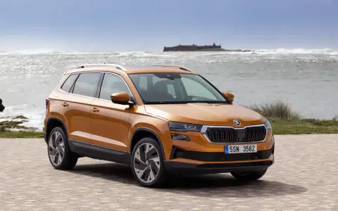 Pomarańczowy Skoda Karoq na tle morza. Sprawdź aktualną skoda karoq cena i wybierz swój wymarzony SUV.