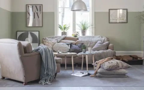 Vardagsrum i svensk stil med bekväm soffa, fåtölj och en sovande hund. Vårljus strömmar in genom fönstret och skapar en mysig atmosfär.