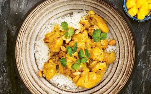 En krämig kycklingcurry med ris, toppad med koriander och jordnötter. En riktig curry nam nam!
