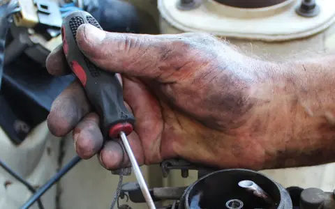 Brudna ręka mechanika z kluczem, naprawia coś w samochodzie. Może to być związane z linki skrzyni biegów objawy.