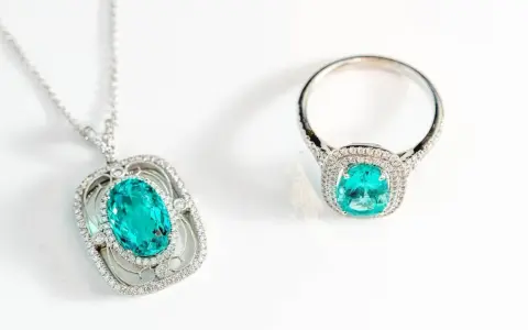 Conjunto de collar y anillo con una deslumbrante piedra de geminis turquesa rodeada de diamantes, sobre fondo blanco.