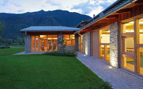 Agriturismi con fattoria immersi nel verde, con architettura in pietra e legno, illuminati al tramonto.