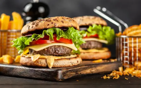 Dwa soczyste hamburgery z serem, sałatą i pomidorem, podane z frytkami.