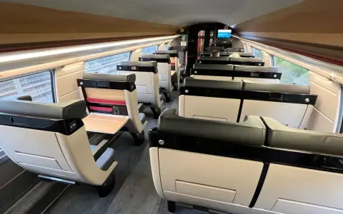 Interior of a modern train carriage, likely the Paris to Bilbao train, with rows of comfortable, beige and black seats.