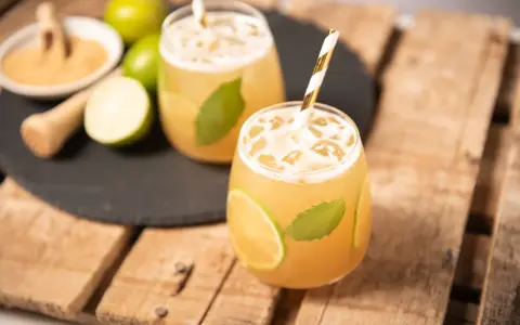 Erfrischender cocktail mit braunem rum, Limette und Minze, serviert mit Eis und einem gestreiften Strohhalm.