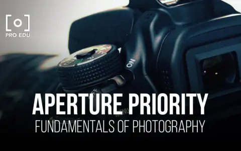 Gros plan sur un appareil photo, avec le texte "APERTURE PRIORITY" et "FUNDAMENTALS OF PHOTOGRAPHY". Le mode priorité ouverture est essentiel pour maîtriser la profondeur de champ.