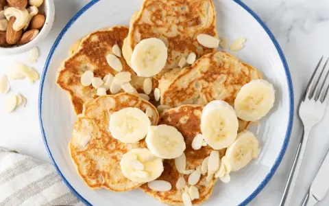 Deliciosas tortitas de plátano, cubiertas con rodajas de plátano y almendras laminadas. Un desayuno perfecto.