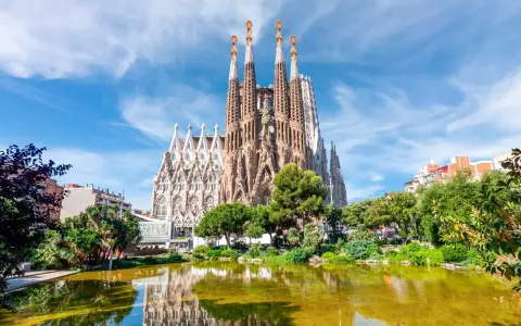 La Sagrada Familia, con le sue torri svettanti e il riflesso sull'acqua, sembra un sogno che attende il suo completamento. Chissà quando finirà la Sagrada Familia.