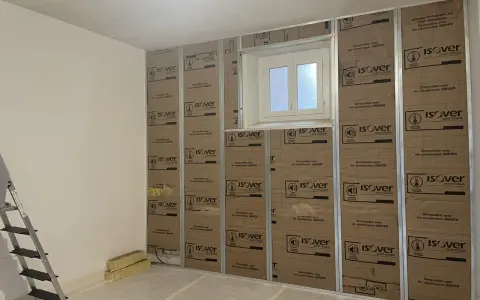 Pose de laine de verre ISOVER en 2 couches sur une structure métallique, avec une fenêtre au centre.