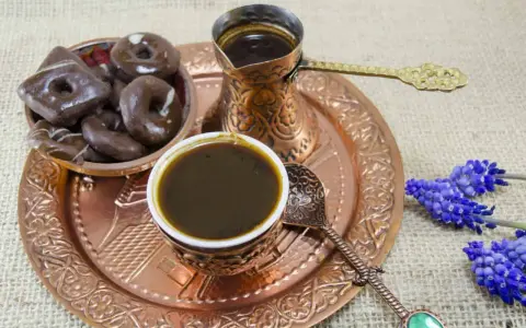 Ein traditionelles Mokkakännchen mit starkem Kaffee, dazu Schokoladenkekse und blaue Blumen. Was ist Mokka? Ein Genuss für die Sinne.