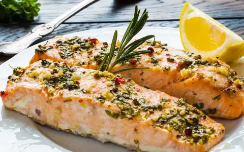 Två saftiga laxfiléer med en härlig pesto-topping, garnerade med rosmarin och en citronklyfta.