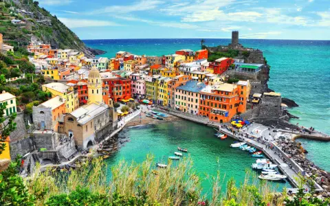 Vernazza, una delle Cinque Terre, con case colorate a picco sul mare turchese e un porticciolo pieno di barche.