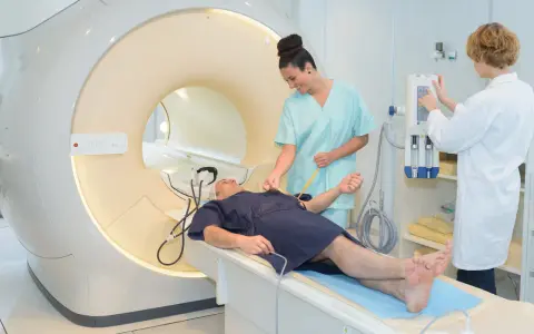 Pacjent na stole do rezonansu magnetycznego, przygotowywany przez pielęgniarki. Szybkie wyniki badań to klucz do diagnozy.