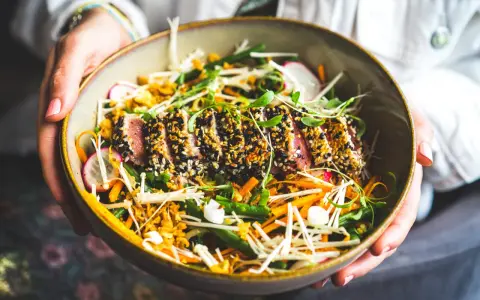 Un délicieux tataki de thon, enrobé de sésame noir et blanc, repose sur un lit de légumes croquants : haricots verts, carottes râpées, radis et champignons enoki.