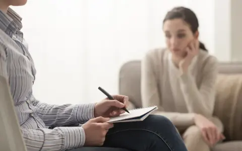 Psycholog kliniczny notuje podczas sesji. Zastanawiasz się, ile zarabia psycholog kliniczny prywatnie?