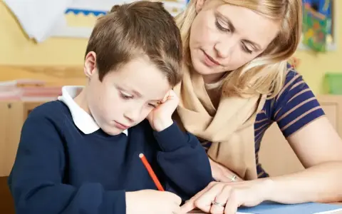 Nauczycielka pomaga chłopcu w nauce, wspierając go w odrabianiu lekcji. Dzięki subwencji oświatowej możliwe jest zapewnienie takich indywidualnych konsultacji.