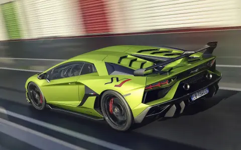 Un espectacular Lamborghini Aventador verde acelera en la pista, con su alerón trasero y detalles aerodinámicos en negro.
