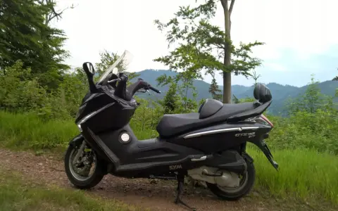 Czarny skuter Sym GTS 125 na górskiej drodze. Jego prędkość maksymalna pozwala na odkrywanie malowniczych zakątków.