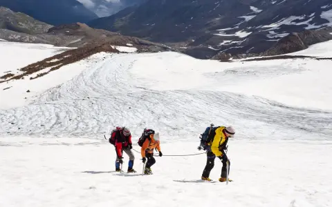 Drei Bergsteiger seilen sich über einen eisigen Gletscher in den Alpen ab.