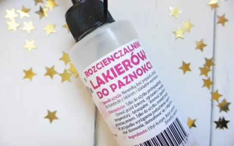 Butelka rozcieńczalnika do lakierów do paznokci z czarną zakrętką i złotymi gwiazdkami.