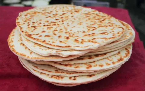 Una pila di piadine dorate, appena sfornate, con macchie di cottura che invitano a gustare questo classico della cucina romagnola.