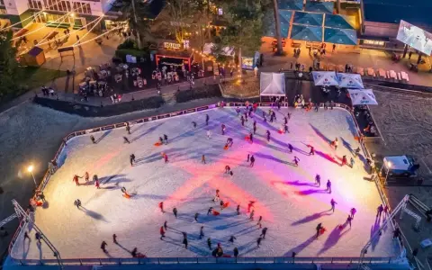 Ein belebter weihnachtsmarkt mit schlittschuhbahn. Menschen gleiten über das Eis, während Lichter die Szene in warme Farben tauchen.