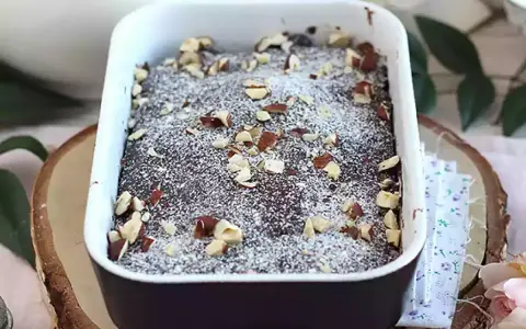 Pyszny brownie z mikrofali, posypany cukrem pudrem i orzechami, w białej ceramicznej formie.