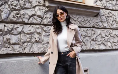Elegancka kobieta w beżowym płaszczu i ciemnych jeansach. Spódnica jeansowa midi stylizacje na co dzień.