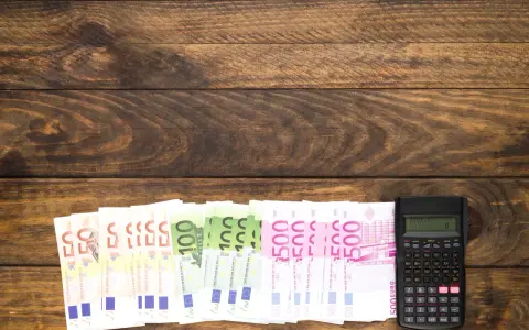 Banknoty euro i kalkulator na drewnianym tle.