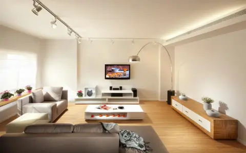 Iluminar un salón moderno con luces de riel y lámpara de arco. Sofás grises, mesa de centro blanca y mueble de TV.