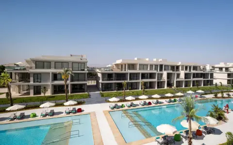 Nowoczesne budynki hotelowe Rixos z basenami i leżakami pod palmami.