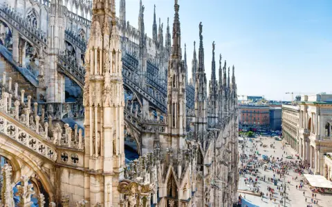 Majestatyczne iglice katedry Duomo w Mediolanie w listopadzie, z widokiem na tętniący życiem plac poniżej.
