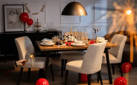 Stół nakryty do kolacji, świece, balony i sztuczne ognie tworzą atmosferę imprezy w stylu lat 70.