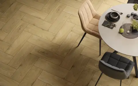 Eleganckie wnętrze z podłogą w jodełkę. Okrągły stół z krzesłami, nakryty do posiłku.