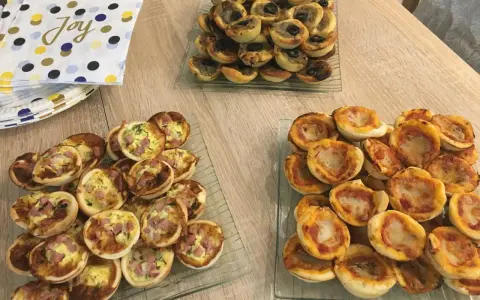 Plateaux de mini-pizzas et quiches, parfaits pour une idée repas crémaillère conviviale.