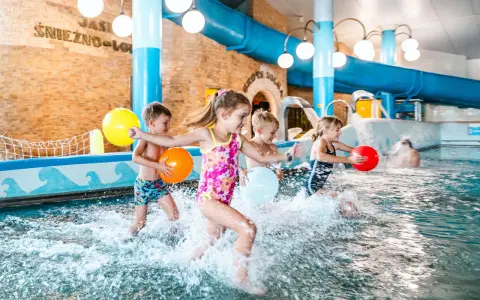 Dzieci bawią się w basenie, rzucając kolorowymi piłkami. Idealne miejsce na rodzinny wypoczynek - hotel z basenem dla dzieci Podlaskie.