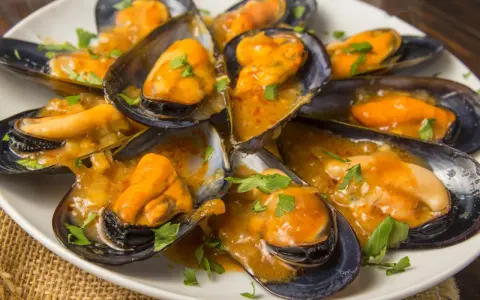 Mejillones en salsa, humeantes y listos para disfrutar. Un plato delicioso con un toque de perejil fresco.